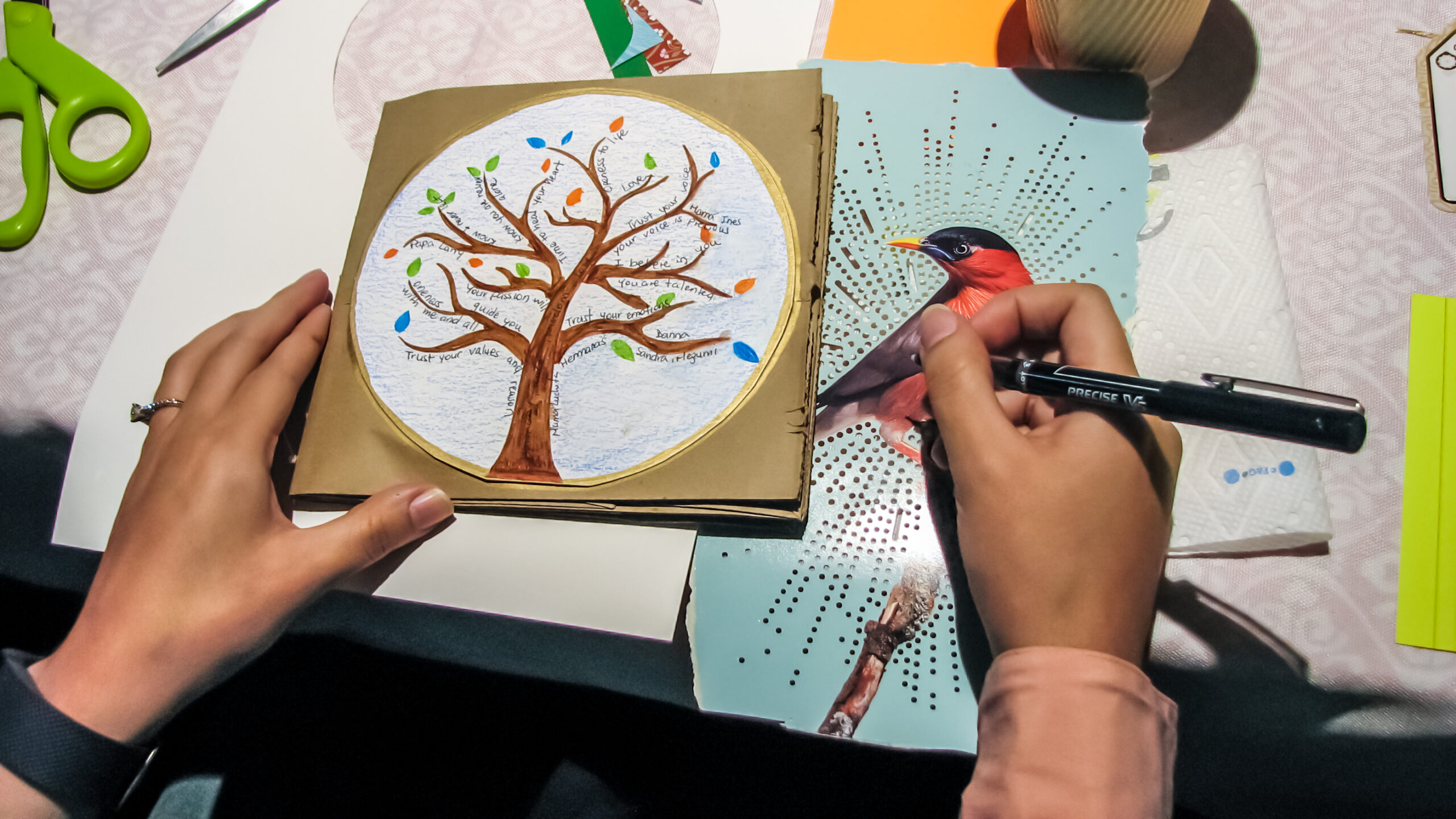 Workshop-Reiki-Art-001-0113 Hands creating a handmade art piece featuring a tree with messages, during a workshop inspired by Prodigal Daughter.